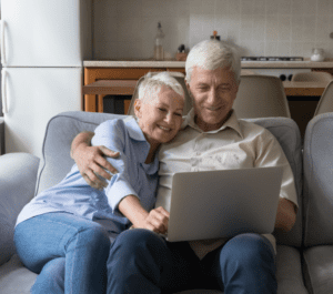 Voksent par som sietter i sofa og ser på en laptop